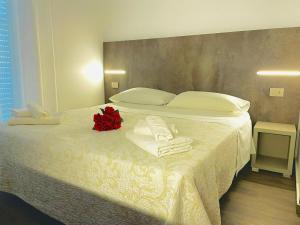 a bed with towels and a red flower on it at Hotel Okinawa in Rimini