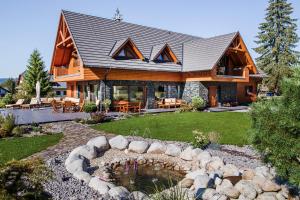a log home with a pond in the yard at Villa Silvia in Zuberec