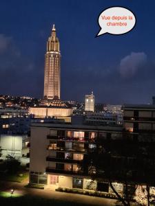 a city skyline with a clock tower at night at LE COCON DE JADE, LA MER A PERTE DE VUE in Le Havre