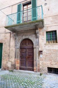 - Edificio con puerta de madera y balcón en BIBO'S GUESTHOUSE en SantʼAngelo in Vado