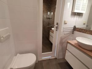 a white bathroom with a toilet and a sink at Motyl Noclegi Bytom in Bytom