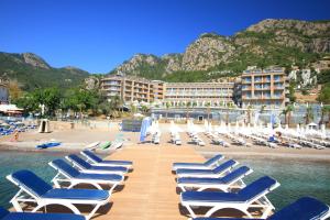 een rij ligstoelen op een strand met een resort bij Turunc Premium Hotel in Turunc