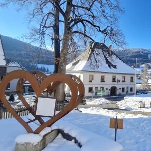 eine Herzstatue im Schnee vor einem Gebäude in der Unterkunft Gasthof Kreischberg in Sankt Georgen ob Murau