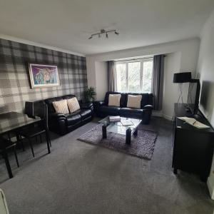 a living room with a couch and a table at Levenhowe Holiday Apartment in Balloch