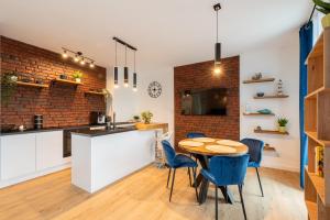 Una cocina y un comedor con una mesa y sillas azules. en Horyzont Apartamenty -Bałtycka2 - SAUNA & FITNESS - ŚNIADANIA, en Kołobrzeg