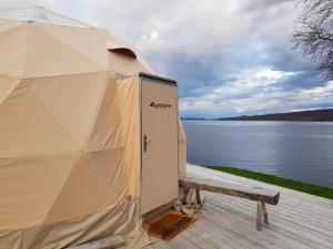 a large tent with a bench in front of a lake at Røros Arctic Dome in Glåmos