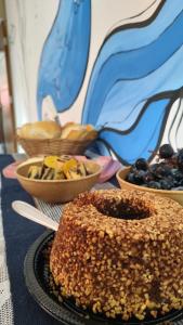 una mesa cubierta con tazones de fruta y un pastel en Tiwá Hostel - antigo DaSanta - CENTRO en Arraial d'Ajuda