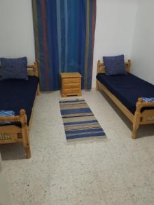 a room with two beds and a nightstand and a table at Dar Janis Djerba دار يانيس جربة in Houmt Souk