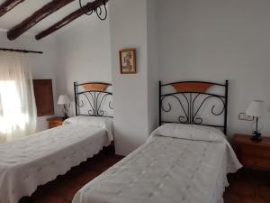 2 camas en una habitación con paredes blancas en Casa Rural Cortijo la Jimena, en Caravaca de la Cruz