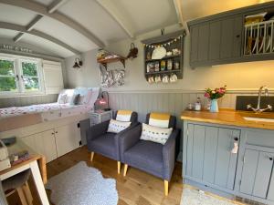 una pequeña cocina con sofá y silla en una habitación en Poachers Hut at Keepers Cottage - Hot Tub & Pizza Oven - Trossachs, en Port of Menteith
