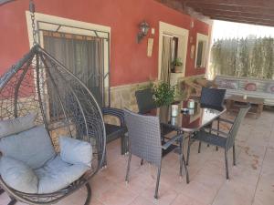 カラバカ・デ・ラ・クルスにあるCasa Rural Cortijo la Jimenaのポーチ(テーブル、椅子、ブランコ付)
