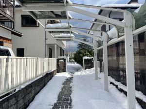 a snow covered sidewalk with a white pergola at 高島市一棟貸切 Biwa Lake琵琶湖 徒歩10分 大人数でご利用だとお得連泊がお得BBQ麻雀可能自転車無料利用可 in Takashima
