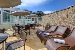 a patio with chairs and tables and a stone wall at Cordilheira Hotel in Serra Negra