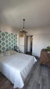 Un dormitorio con una gran cama blanca y una mesa en Alquiler temporario en Villa Urquiza en Buenos Aires
