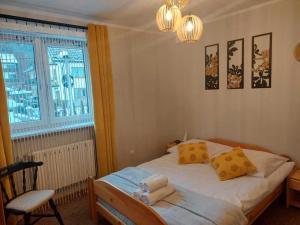 a bedroom with a bed with yellow pillows and a window at Domek nad potokiem in Kluszkowce