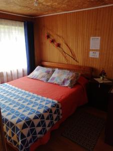 Un pequeño dormitorio con una cama con una sábana roja y una ventana en "Mi Hostal Tu Casa" Hostal Familiar SOLO EMPRESAS, TURISTAS y VIAJEROS, en Puerto Montt