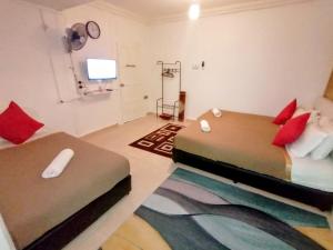 a bedroom with two beds with red pillows and a television at Fishing Village Marang Terengganu in Marang
