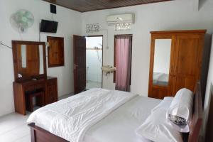 a bedroom with a white bed and a mirror at Karauci Homestay in Abeansemal