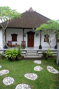 a garden in front of a white house with trees at Karauci Homestay in Abeansemal