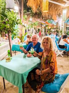 a man and woman sitting at a table with drinks at Zipp Bar Restaurant & Bungalows in Gili Islands