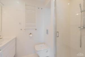 a white bathroom with a toilet and a shower at Horyzont Apartamenty - Osiedle Bursztynowe- Śniadania!!! in Kołobrzeg