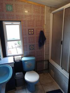 a bathroom with a blue toilet and a sink at "Mi Hostal Tu Casa" Hostal Familiar SOLO EMPRESAS, TURISTAS y VIAJEROS in Puerto Montt