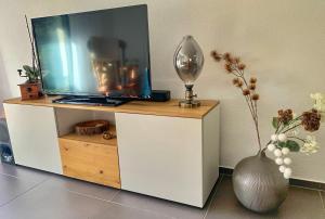 einen TV auf einem weißen Schrank mit einer Vase in der Unterkunft Büelbad - Relax Holiday Apartment in Kandersteg