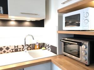 una cocina con microondas y fregadero en LE NOIR BOIS ET BLANC - Studio - Wifi - Centre Ville - Entrée Autonome, en Quimper