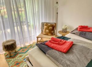 ein Schlafzimmer mit einem Bett, einem Stuhl und einem Fenster in der Unterkunft Büelbad - Relax Holiday Apartment in Kandersteg