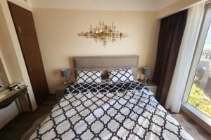 a bedroom with a black and white bed with a chandelier at Cozy 1BR in Gate Tower in Abu Dhabi