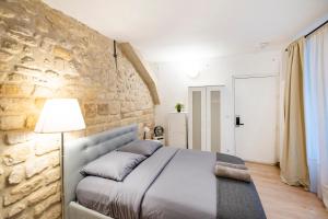 パリにあるParis entre Opéra et Montmartreの石壁のベッドルーム1室(ベッド1台付)