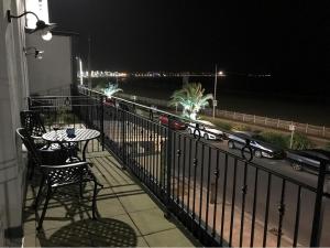 a balcony with a table and chairs and the ocean at night at Beachfront with balcony 1st Floor apartment "The Beaches" in Weymouth