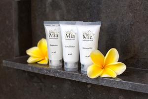 a shelf with three moisturizers and yellow flowers on it at Villa Mia Seminyak - Boutique Villas in Seminyak