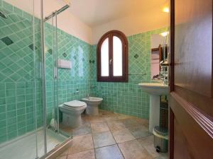 a green tiled bathroom with a toilet and a sink at Casa Vacanza la Suaredda in San Teodoro