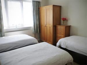 a bedroom with two beds and a cabinet and a window at Daisychain Holidays in Bridlington