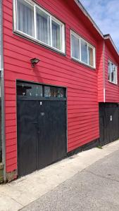 un bâtiment rouge avec un grand garage noir dans l'établissement "Mi Hostal Tu Casa" Hostal Familiar SOLO EMPRESAS, TURISTAS y VIAJEROS, à Puerto Montt