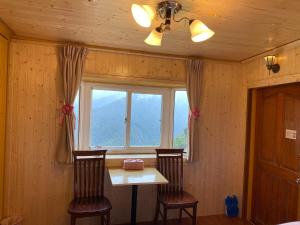 Zimmer mit einem Tisch, 2 Stühlen und einem Fenster in der Unterkunft La La Shan 5.5KNong Zhuang in Hualing