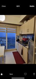 a kitchen with white cabinets and a large window at Wind Residences in Tagaytay