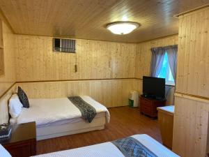 ein Schlafzimmer mit 2 Betten und einem TV. in der Unterkunft La La Shan 5.5KNong Zhuang in Hualing