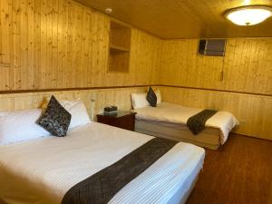 two beds in a room with wooden walls at La La Shan 5.5KNong Zhuang in Hualing