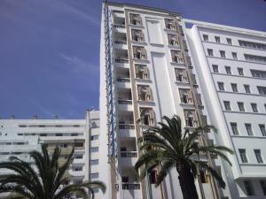 un grand bâtiment blanc avec des palmiers devant lui dans l'établissement Hotel Moroccan House Casablanca, à Casablanca