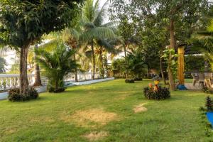 a yard with palm trees and a fence at Brit's Palace Goa in Agacaim