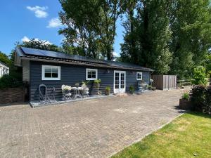 a small blue house with a patio in a yard at B & B d’ Uitwijkerpoort 