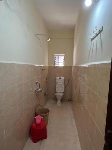 a bathroom with a toilet and a red bucket at New Bombay Lodge in Nagpur