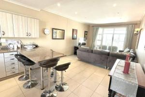 eine Küche und ein Wohnzimmer mit einer Theke und Stühlen in der Unterkunft Luxury at Pinnacle Point - 3 Bedroom Villa in DʼAlmeida