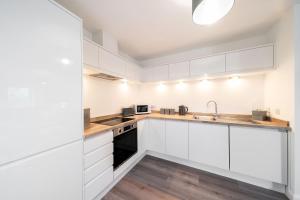 uma cozinha com armários brancos e um lavatório em South Esk Apartment 5 em Montrose