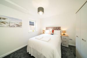 a white bedroom with a bed and a window at South Esk Apartment 5 in Montrose