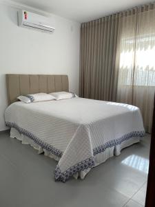 1 dormitorio con 1 cama blanca grande y ventana en B e l a V i s t a, en Porto Seguro
