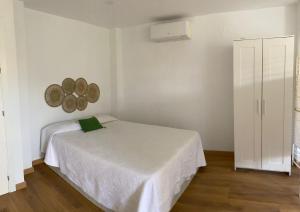 um quarto com uma cama branca e um armário branco em Estudio Pedregalejo Garden Málaga em Málaga