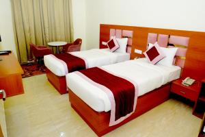 a hotel room with two beds and a table at Twin Towers Inn in Greater Noida